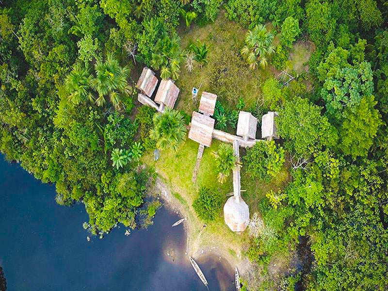 Aerial view from above Antares Amazon Lodge surrounded by lush green rainforest, showcasing eco-friendly cabins and natural landscape in the heart of the Peruvian Amazon.