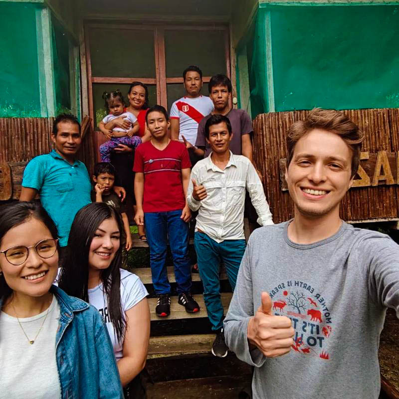 Tourists and lodge staff smiling and posing at the entrance of the lodge dining area, surrounded by a welcoming natural environment