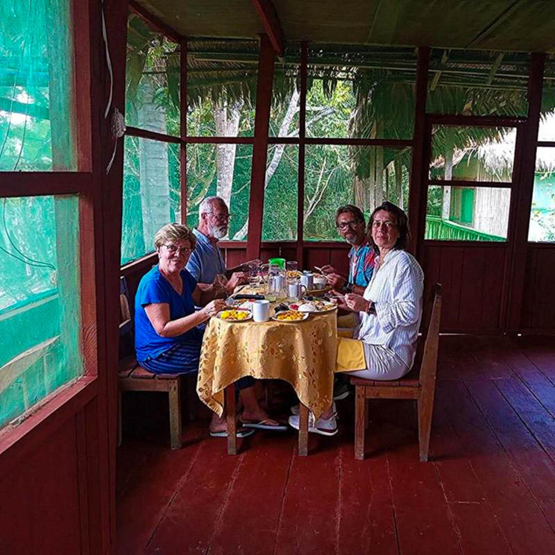 Tourists enjoying lunch in the dining room of Antares Amazon Lodge, surrounded by tropical rainforest views and natural Amazon decor