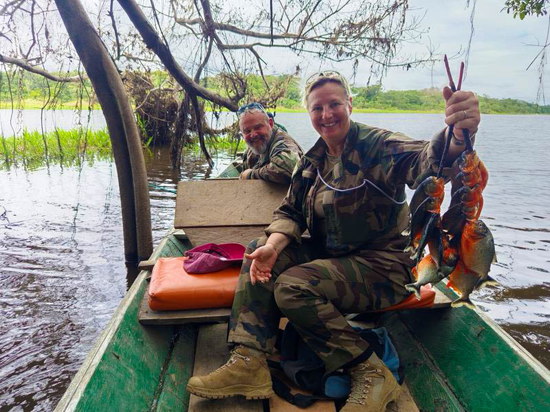 Tourists holding a rope with freshly caught piranhas by the edge of a lake